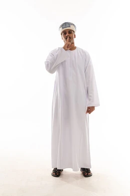 وضع اصبع السبابة على الفم اشارة الي طلب السكوت و التوقف عن الكلام , رجل عربي خليجي عماني يرتدي الدشداشة البيضاء و العمامة , الوقوف امام الكاميرا , الجسم بالطول الكامل , بورتريه خلفية بيضاء