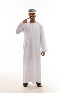 الاشارة الى الاسنان البيضاء الصحية باصبع السبابة , رجل عربي خليجي عماني يرتدي دشداشة بيضاء و عمامة يقف امام الكاميرا , تعابير الابتسامةو السعادة , بورتريه خلفية بيضاء , الجسم بالطول الكامل