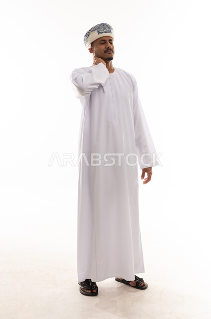 وضع اليد على الرقبة علامة على الوجع الشديد , رجل عربي خليجي عماني يرتدي الدشداشة البيضاء و العمامة , تعابير الشعور بالالم و الاعياء , الجسم بالطول الكامل , بورتريه خلفية بيضاء