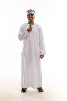 Standing in front of the camera and smiling, an Arab Gulf Omani man wearing a white dishdasha and a turban holding a microphone, enjoying while singing, expressions of happiness, portrait with a white background, full body.
