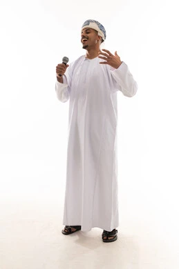 قضاء الاوقات المسلية اثناء الغناء , رجل عربي خليجي عماني يرتدي دشداشة بيضاء و عمامة يحمل الميكروفون , تعابير السعادة و الفرحة , رفع اليد لاعلى اشارة الي الاستمتاع و الاندماج في النشاط المسلي , خلفية بيضاء , بورتريه بالطول الكامل للجسم