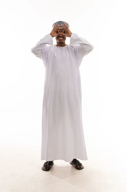 رجل عربي خليجي عماني يرتدي الدشداشة البيضاء و العمامة يقوم بعمل حركة دائرية باصبعي السبابة و الابهام اما العين اشارة الي المنظار المقرب , النظر بسعادة الي شئ ما , بورتريه الطول الكامل للجسم , خلفية بيضاء