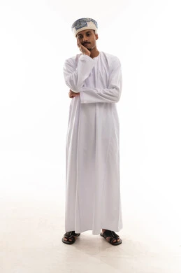 The hand placed on the cheek is a sign of frustration and sadness, an Arab Gulf Omani man wearing a white dishdasha and turban, gestures of discomfort and distress, standing in front of the camera, full body, portrait with a white background.