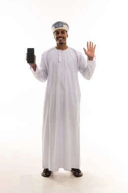 فتح قبضة اليد اشارة على الترجيب و السلام , رجل عربي خليجي عماني يرتدي دشداشة بيضاء و عمامة يعرض شاشاة هاتف محمول سوداء فارغة , بورتريه طول كامل للجسم , خلفية بيضاء