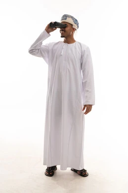 استخدام المنظار المقرب للنظر الى شئ ما , رجل عربي خليجي عماني يرتدي الدشداشة البيضاء و العمامة ينظر الى الاشياء البعيدة , ايماءات السرور , بورتريه الجسم بالطول الكامل ,  خلفية بيضاء