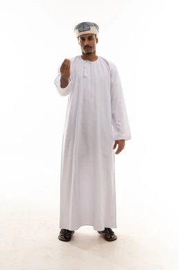 ضم اصابع كف اليد و رفع الذراع امام الكاميرا اشارة الي طلب التمهل و عدم التسرع , رجل عربي خليجي عماني يرتدي دشداشة بيضاء و عمامة يقوم باشارة طلب الانتظار و التمهل , الجسم بالطول الكامل , بورتريه خلفية بيضاء