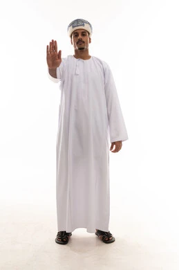 وضع كف اليد امام الكاميرا علامة على التوقف و طلب الوقوف , رجل عربي خليجي عماني يرتدي دشداشة بيضاء و عمامة , بورتريه خلفية بيضاء , الجسم بالطول الكامل , علامة ممنوع الاقتراب اكثر  , تعابير الاستياء و الضيق