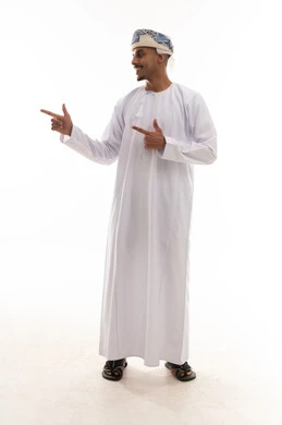 رفع اصبعي السبابة للجانب اشارة الي شئ ما , رجل عربي خليجي عماني يرتدي الدشداشة البيضاء و العمامة , النظر الي الجانب , الجسم بالطول الكامل , خلفية بيضاء
