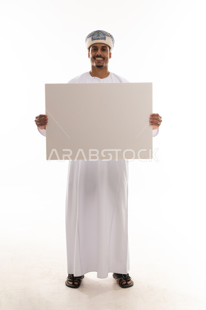An Arab Gulf Omani man wearing a traditional white thobe in the Sultanate of Oman and a turban, holding a large paper, looking directly at the camera, with gestures of joy and happiness, full-body shot, portrait with a white background.
