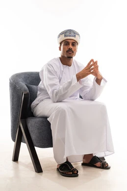 نظرة امامية للكاميرا مع وضع اصابع اليدين متقابلين , رجل عربي خليجي عماني يرتدي العمامة و الدشداشة التقليدية , تعابير الحيرة قبل اتخاذ القرار الصحيح