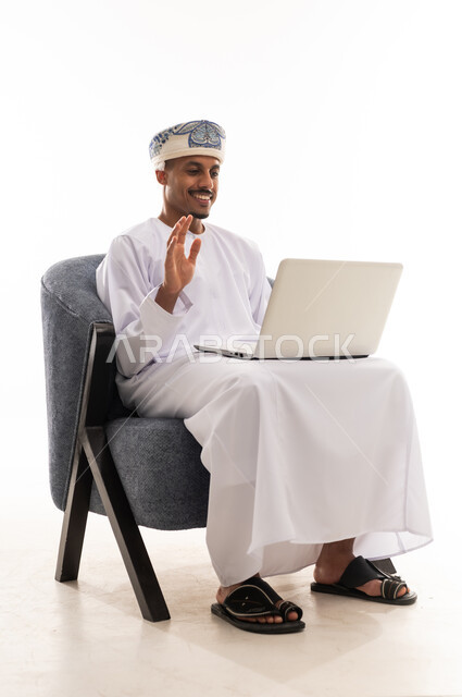 التلويح باشارة الترحيب اثناء عقد الاجتماعات الجماعية المباشرة , رجل عربي خليجي عماني يحمل الحاسوب المتنقل بسهولة , تعابير السعادة و الفرحة , بورتريه خلفية بيضاء , الجسم بالطول الكامل