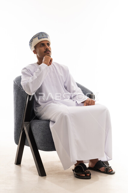 الاستغراق في التفكير العميق , رجل عربي خليجي عماني يرتدي دشداشة بيضاء و العمامة ينظر للاعلى الى شئ ما , تعابير الحيرة في الوصول الي القرار , الجسم بالطول الكامل , بورتريه خلفية بيضاء