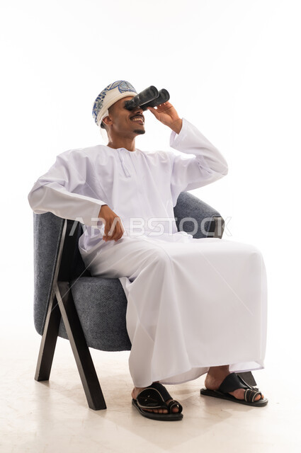 خاصية التقريب الاشياء و تكبير الاجسام البعيدة , رجل عرب خليجي عماني يرتدي دشداشة بيضاء و عمامة يحمل المنظار المقرب و ينظر للاعلى الى  شئ ما ,الجسم بالطول الكامل , بورتريه حلفية بيضاء