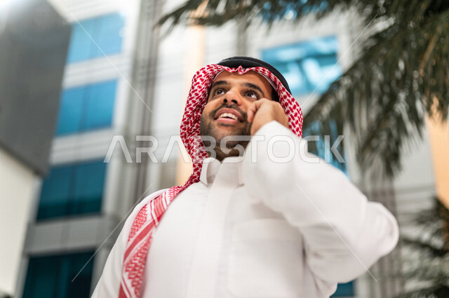 رجل خليجي سعودي ، يقوم بإجراء مكالمة هاتفية عبر الهاتف المحمول في داخل الفندق السياحي ، إستخدام أجهزة تقنية حديثة ، جلسة عمل، مفهوم إدارة الأعمال، عقد صفقات تجارية ، العمل عن بعد ، التسويق الإلكتروني، رحلة عمل ، سياحة وفندقة ، سياحة وسفر