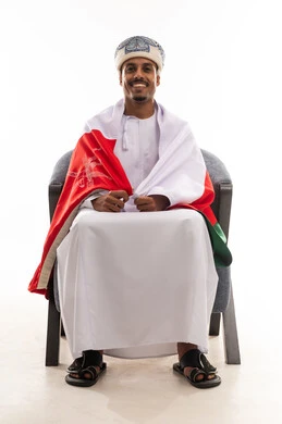 A Gulf Arab Omani man carrying the Omani flag on his shoulders, looking directly at the camera with a smile, portrait with a white background, full body.