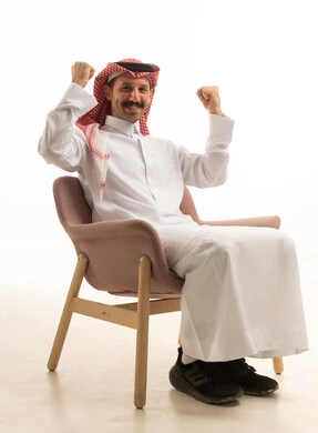 رجل سعودي يجلس على كرسي يحتفل بالنجاح