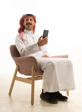 رجل سعودي بالزي التقليدي يستخدم هاتف ذكي في استوديو