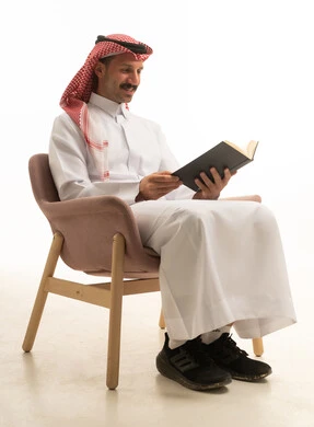 رجل سعودي بالزي التقليدي يقرأ كتاباً في الاستوديو