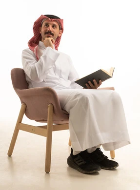 رجل سعودي بالثوب التقليدي يقرأ كتاباً