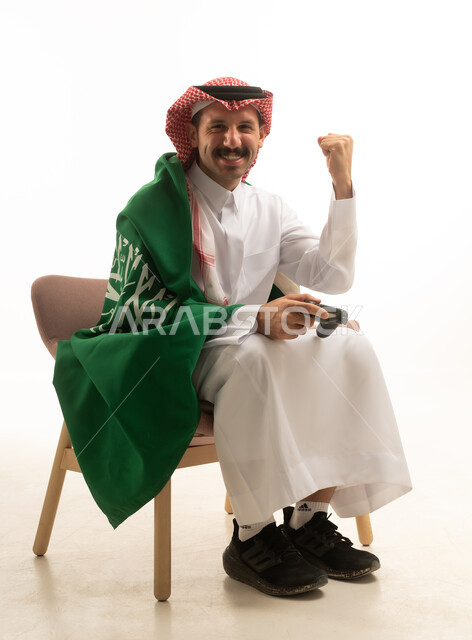 احتفال رجل سعودي يلعب ألعاب الفيديو مع العلم السعودي