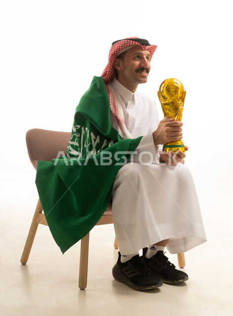 رجل سعودي يحمل كأس العالم مع العلم السعودي