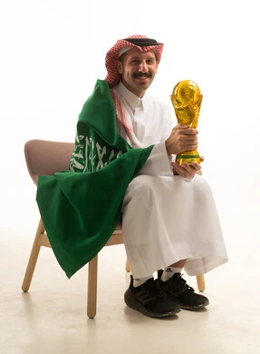 رجل سعودي يحمل كأس العالم مع العلم السعودي