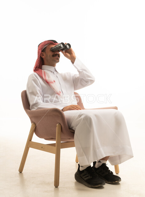 رجل سعودي يجلس في استوديو ويستخدم المنظار