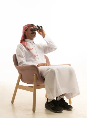رجل سعودي يجلس في استوديو ويستخدم المنظار