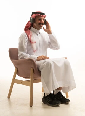 رجل سعودي يرتدي سماعات رأس في استوديو بخلفية بيضاء