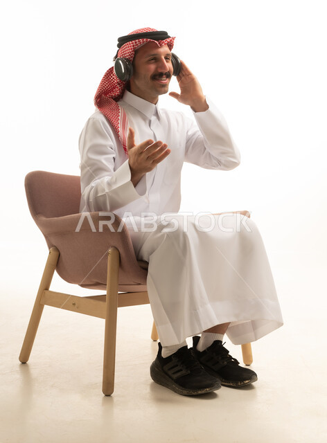 رجل سعودي يرتدي سماعات الرأس ويجلس على كرسي