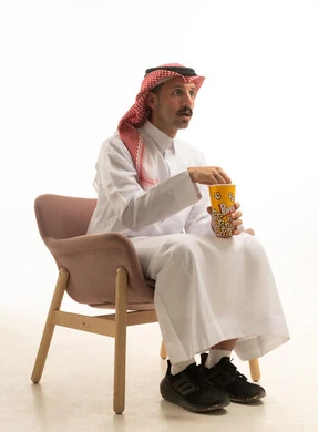 رجل سعودي بالزي التقليدي يتناول الفشار