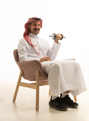 رجل سعودي يرتدي الثوب التقليدي يرفع الأثقال بخلفية بيضاء