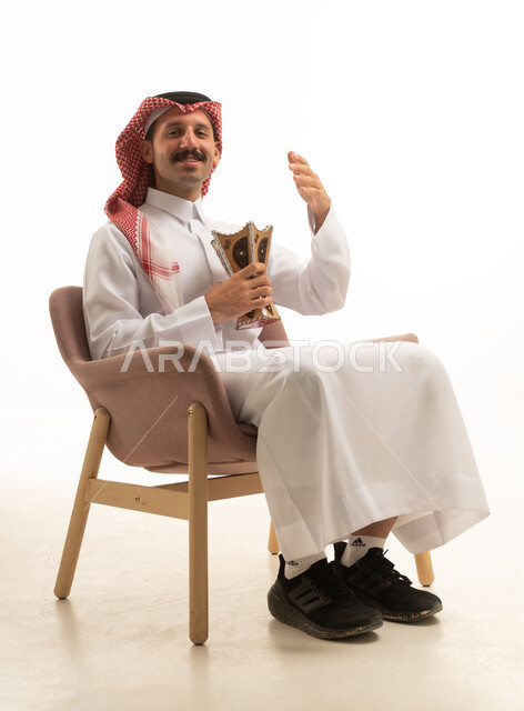 رجل سعودي بالزي التقليدي يحمل مبخرة بخور