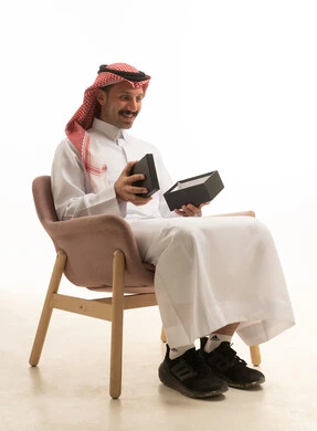 رجل سعودي يفتح صندوق هدايا في استوديو أبيض