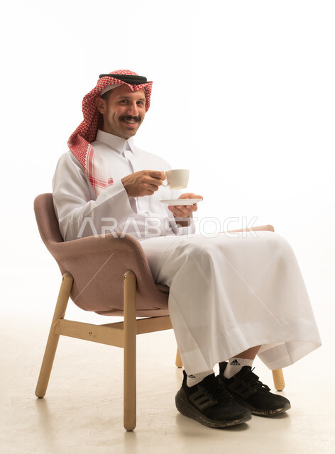 رجل سعودي بالزي التقليدي يشرب القهوة في الاستوديو