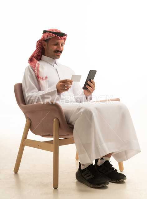 رجل سعودي يستخدم الهاتف والبطاقة الائتمانية