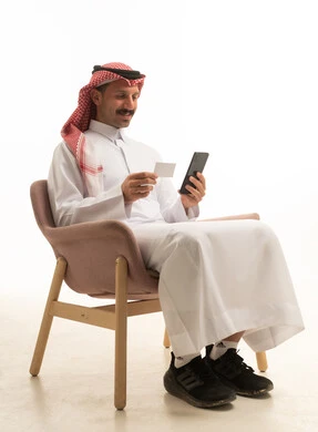 Saudi Man Using Smartphone and Credit Card Indoors