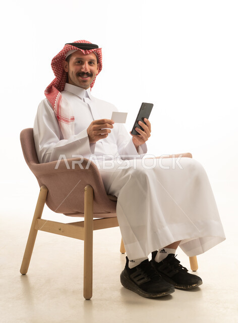 رجل سعودي يستخدم هاتف ذكي وبطاقة ائتمان في استوديو