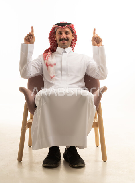 رجل سعودي يرتدي الزي التقليدي يشير للأعلى بالسبابة