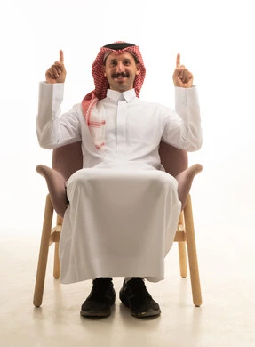 رجل سعودي يرتدي الزي التقليدي يشير للأعلى بالسبابة