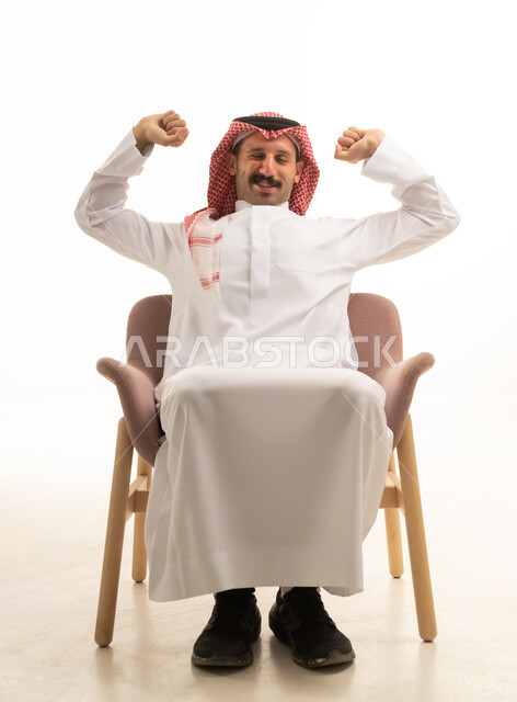 رجل سعودي بالزي التقليدي يمدد ذراعيه على الكرسي