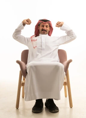 رجل سعودي بالزي التقليدي يمدد ذراعيه على الكرسي