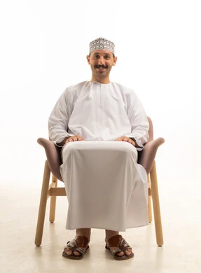 رجل سعودي بالثوب التقليدي يجلس على كرسي في الاستوديو