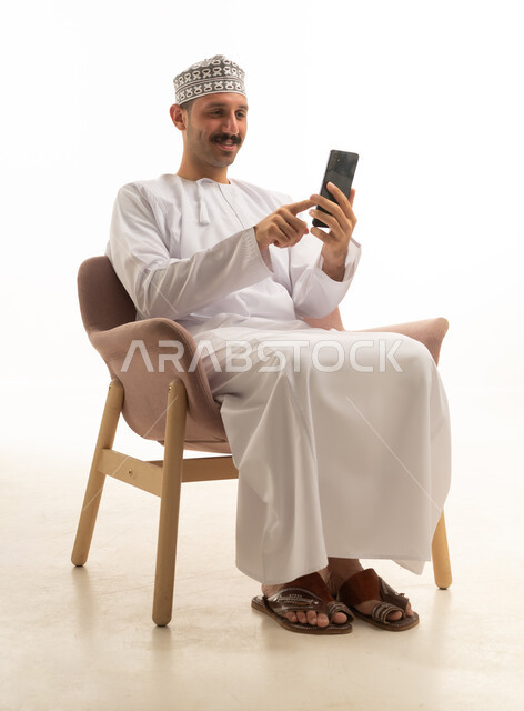 Omani Man in Traditional Dress Using Smartphone