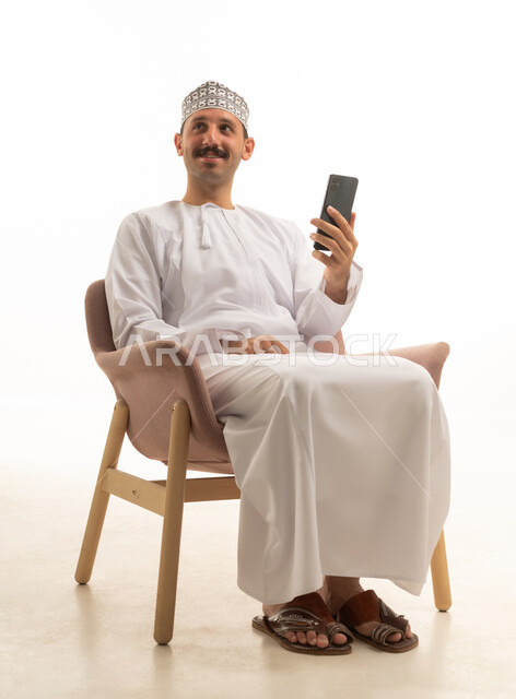 رجل عماني بالزي التقليدي يمسك هاتف ذكي
