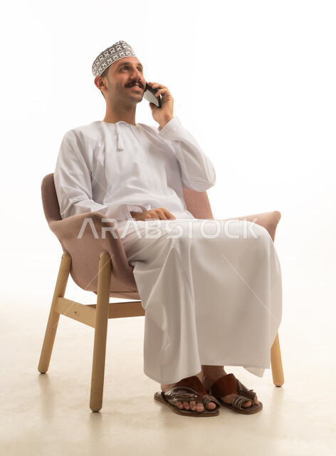 رجل عماني عربي خليجي يرتدي الكمه والدشداشه يجلس على كرسي بايماءات وحركات متنوعه, خلفيه بيضاء