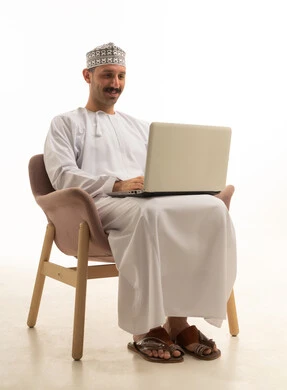 رجل عُماني يستخدم الحاسوب المحمول بخلفية بيضاء