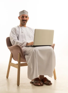 رجل سعودي يستخدم الحاسوب المحمول جالساً على كرسي