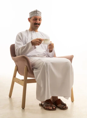 رجل سعودي بالزي التقليدي يمسك فنجان قهوة