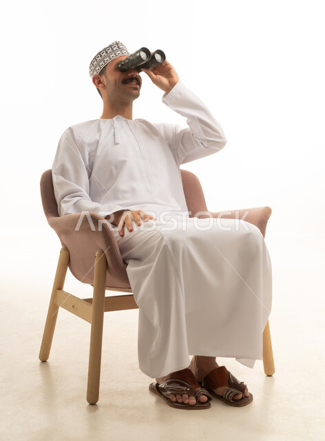 رجل سعودي بالزي التقليدي يستخدم المنظار